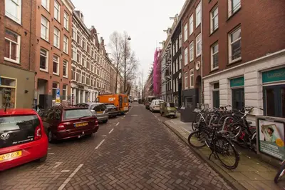 a city street with cars and bikes parked on the street at Het Kabinet in Amsterdam