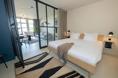 a bedroom with a large bed and a living room at Poort Beach Boutique Apartments in Bloemendaal Aan Zee