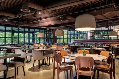 a restaurant with tables and chairs and windows at Corendon Urban Amsterdam Schiphol Airport Hotel in Badhoevedorp