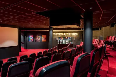 a cinema room with red chairs and a screen at Corendon Urban Amsterdam Schiphol Airport Hotel in Badhoevedorp