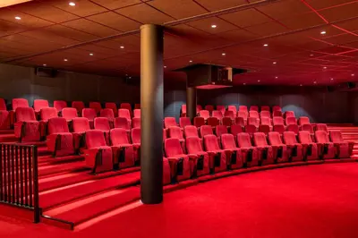 an empty auditorium with red chairs on a red carpet at Corendon Urban Amsterdam Schiphol Airport Hotel in Badhoevedorp