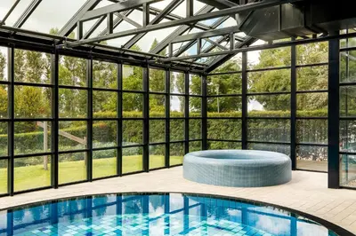 a swimming pool in a glass house with a view at Corendon Urban Amsterdam Schiphol Airport Hotel in Badhoevedorp