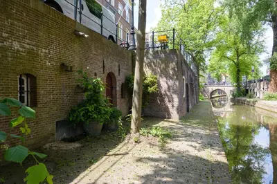 a brick building with a tree next to a canal at Large Historical Apartment & Canal Terrace in Utrecht