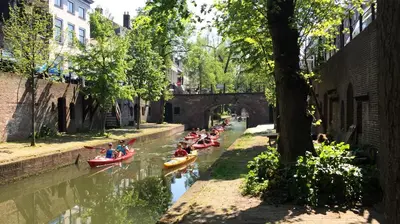 a group of people kayaking down a river in canoes at Large Historical Apartment & Canal Terrace in Utrecht