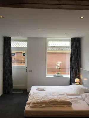 a bedroom with a large bed and a window at Appartementen Rijnhoeve in Koudekerk aan den Rijn
