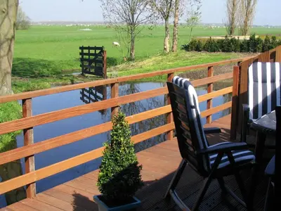 a wooden deck with two chairs and a potted plant at Appartementen Rijnhoeve in Koudekerk aan den Rijn