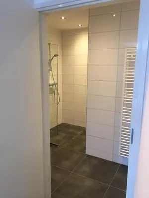 a walk in shower in a bathroom with a mirror at Appartementen Rijnhoeve in Koudekerk aan den Rijn