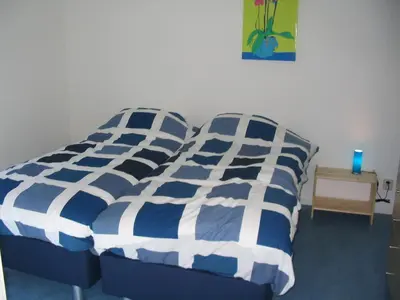 a bedroom with a bed with blue and white sheets at Appartementen Rijnhoeve in Koudekerk aan den Rijn
