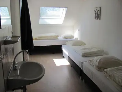 two beds in a room with a sink and a window at Appartementen Rijnhoeve in Koudekerk aan den Rijn