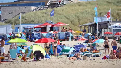 a crowd of people on a beach with umbrellas at Zomerhuis Rita in Egmond aan Zee