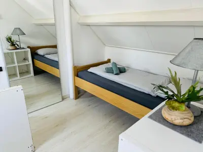 a small bedroom with two beds and a table at Zomerhuis Rita in Egmond aan Zee