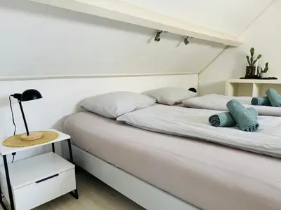 a bedroom with a white bed with blue pillows at Zomerhuis Rita in Egmond aan Zee