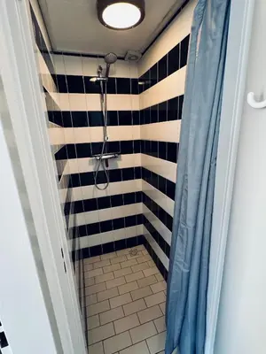 a bathroom with a shower with a black and white tiles at Zomerhuis Rita in Egmond aan Zee