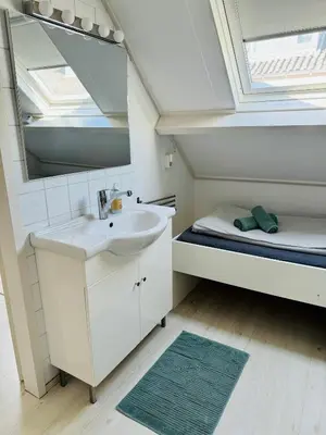 a bathroom with a sink and a mirror and a bed at Zomerhuis Rita in Egmond aan Zee