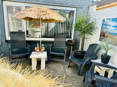 a patio with chairs and an umbrella and a table at Zomerhuis Rita in Egmond aan Zee