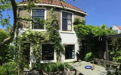 a house with a table in front of it at Apple Tree Cottage - charming home at beautiful canal in our idyllic garden in Gouda