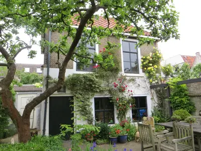 a house with flowers in front of it at Apple Tree Cottage - charming home at beautiful canal in our idyllic garden in Gouda