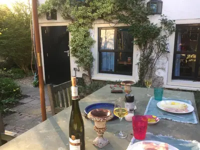 a table with a bottle of wine and glasses on it at Apple Tree Cottage - charming home at beautiful canal in our idyllic garden in Gouda