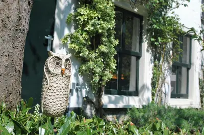 a statue of an owl on the side of a house at Apple Tree Cottage - charming home at beautiful canal in our idyllic garden in Gouda