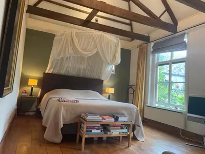 a bedroom with a bed with a canopy and a window at Apple Tree Cottage - charming home at beautiful canal in our idyllic garden in Gouda
