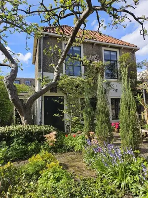 a house with a garden in front of it at Apple Tree Cottage - charming home at beautiful canal in our idyllic garden in Gouda