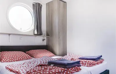 a bed with red and white pillows and a window at Aquacabin in Aalsmeer