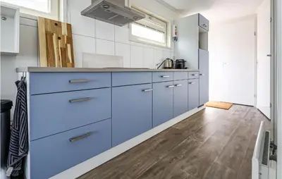 a kitchen with blue cabinets and a wooden floor at Aqualiving in Aalsmeer