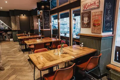 a restaurant with wooden tables and chairs in a room at Hotel Corner House in Amsterdam