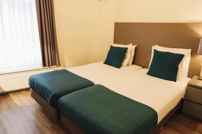 a bedroom with two beds with green pillows at Hotel Corner House in Amsterdam