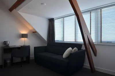 a living room with a couch and a desk and windows at Hotel Restaurant de Engel in Lisse