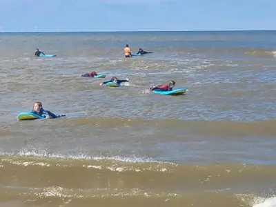 a group of people laying on surfboards in the ocean at Holiday Home Bergen aan Zee near Beach in Bergen aan Zee