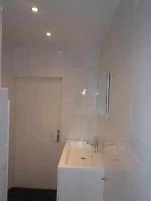 a white bathroom with a sink and a mirror at Appartement Brouwer in Egmond aan Zee