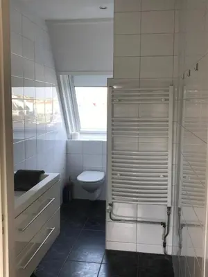 a white bathroom with a toilet and a window at Appartement Brouwer in Egmond aan Zee