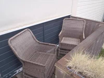 two wicker chairs and a table on a porch at Appartement Brouwer in Egmond aan Zee