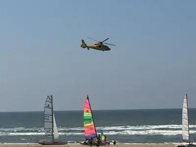 a helicopter flying over the beach with sailboats at Appartement Brouwer in Egmond aan Zee