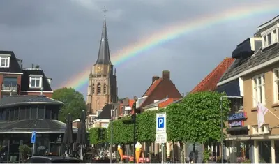 a rainbow in the sky over a city with buildings at Genesis Voorschoten in Voorschoten