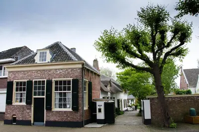 an old brick house with a tree in front of it at Genesis Voorschoten in Voorschoten