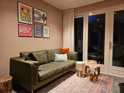 a living room with a green couch and two tables at Zandvoort at Home I Free parking & Airco in Zandvoort
