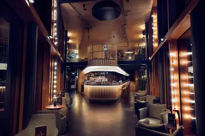 a lobby with a bar in the middle of a building at Hotel Jakarta Amsterdam in Amsterdam