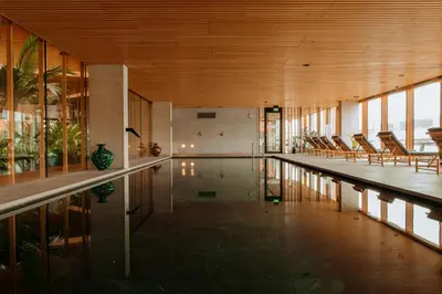 an indoor pool in a building with chairs and a table at Hotel Jakarta Amsterdam in Amsterdam