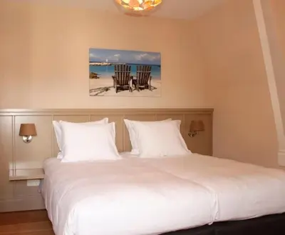 a bedroom with a large white bed with two chairs at Loetje Overveen in Overveen