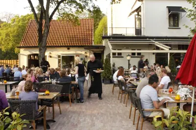 a group of people sitting at tables at a restaurant at Loetje Overveen in Overveen