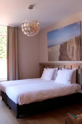 a bedroom with a large bed with a chandelier at Loetje Overveen in Overveen