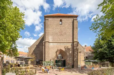 a church with a clock tower with a sign that reads book at Bunk Hotel Amsterdam in Amsterdam