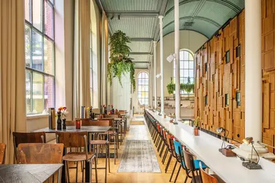 a large room with tables and chairs and windows at Bunk Hotel Utrecht in Utrecht