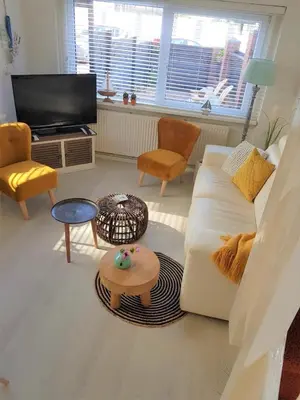 a living room with a white couch and a tv at De Kneet in Egmond aan Zee