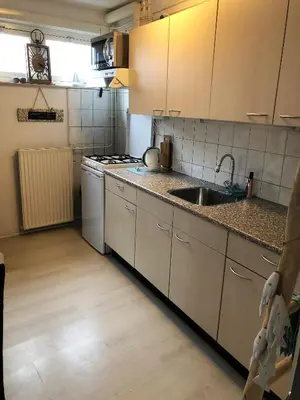 a small kitchen with a sink and a stove at De Kneet in Egmond aan Zee