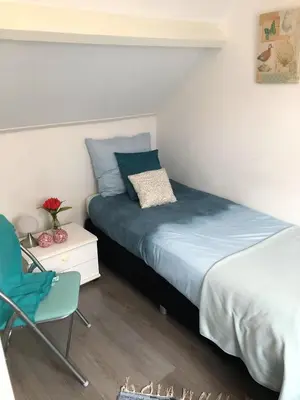 a bedroom with a bed and a chair at De Kneet in Egmond aan Zee