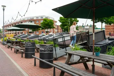 a woman walking past a row of picnic tables with umbrellas at B&B Vita Nova in Amersfoort
