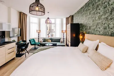 a bedroom with a large bed and a living room at Boutique hotel Margretha in Zandvoort